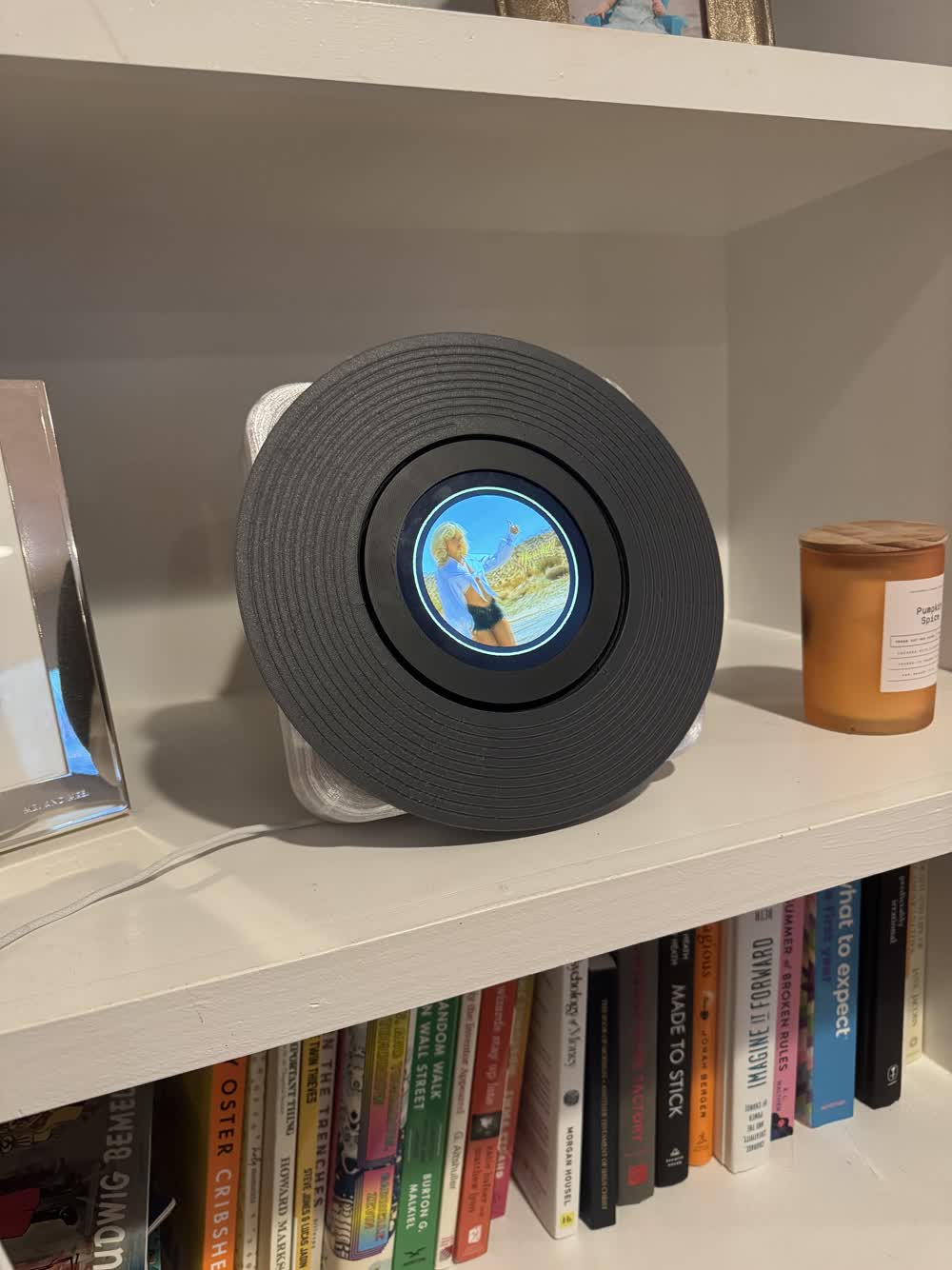 Real SPNDL prototype with a charcoal disc displaying album artwork on a bookshelf